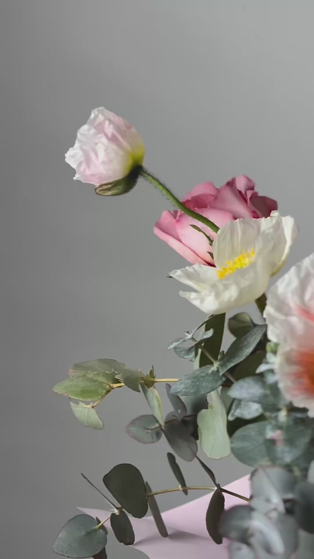 Vibrant flower arrangement in a pastel green box with pink ribbon, featuring poppies, roses, eucalyptus, and delicate blooms from Five Petals Florist.